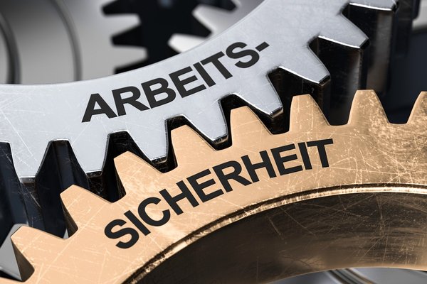 Zwei Zahnräder mit den Aufschriften "Arbeits-" und "Sicherheit" greifen ineinander.