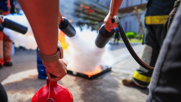Personen in Schutzkleidung löschen ein Übungsfeuer.